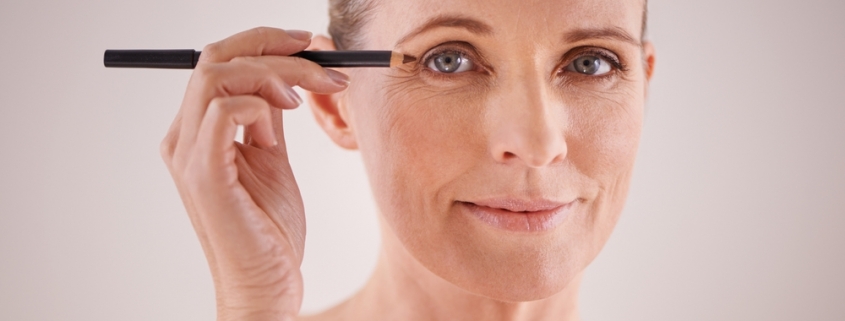 middle aged woman applying eyeliner