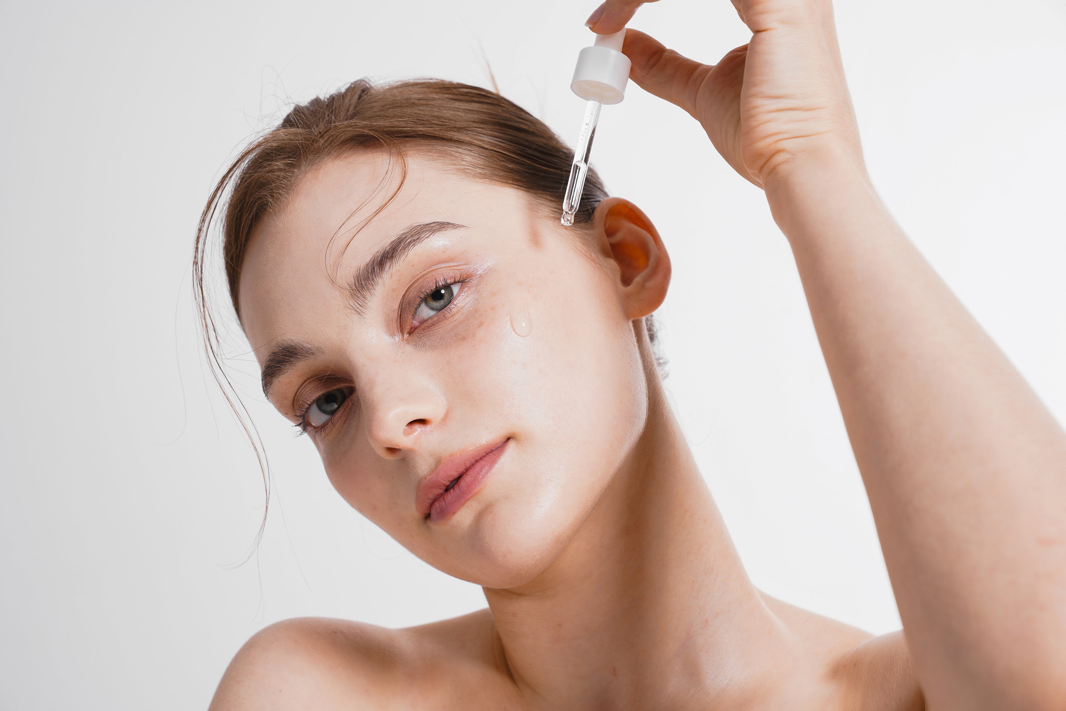 Woman applying skincare serum with dropper for brighter, refreshed under-eye area