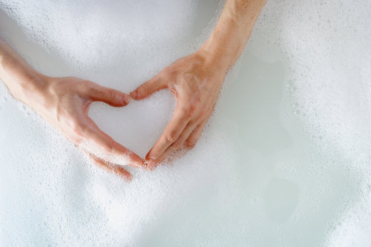 hands forming a heart on what seems to be soap foam and water in a tub