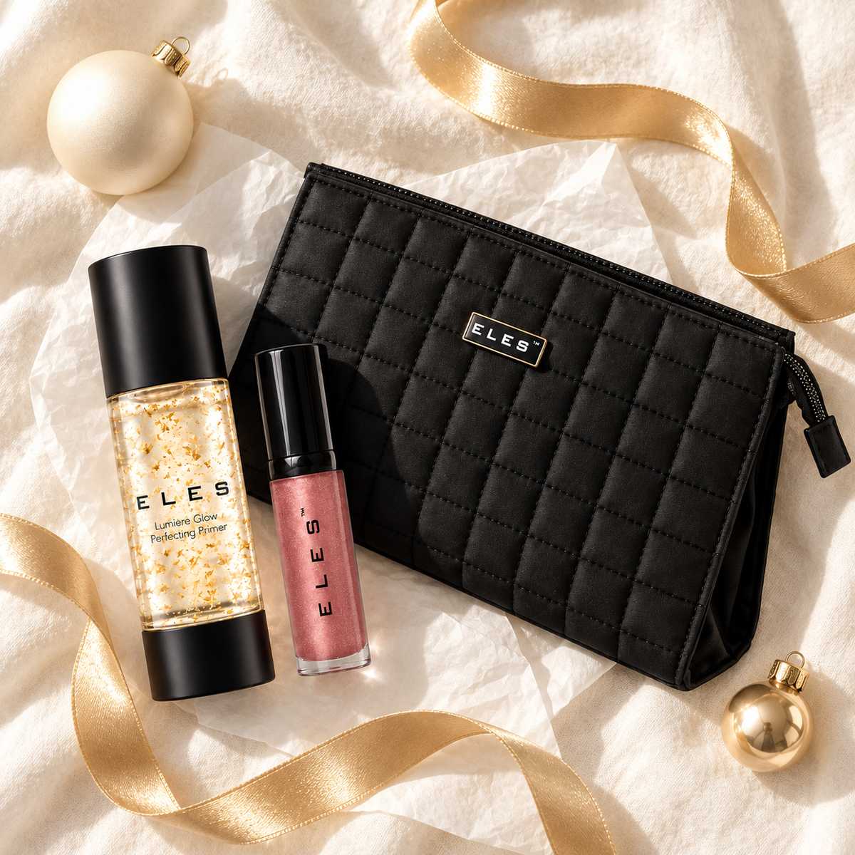Flatlay of ELES Lumiere Glow Perfecting Primer, Demure Colour Balm and black quilted cosmetics bag with gold ribbon and Christmas baubles.
