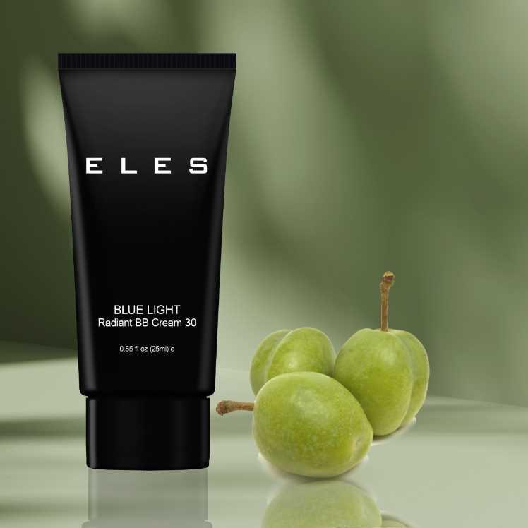 Black tube of ELES Blue Light Radiant BB Cream 30 with green fruits on a reflective surface and green background