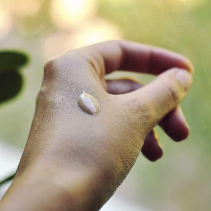 Hand with a droplet of water against a blurred natural background