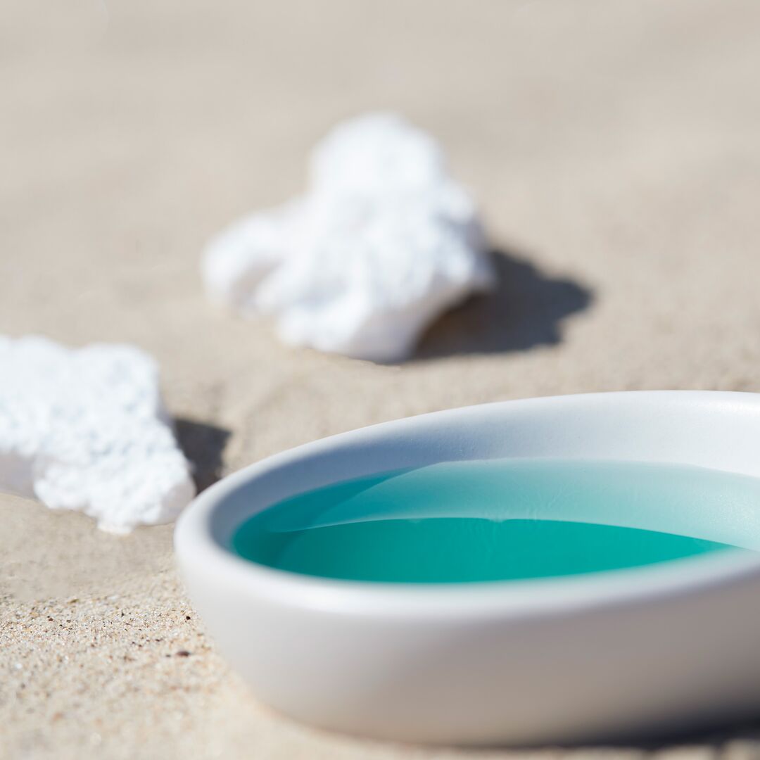 White dish with Phytomer Oligoforce Advanced Serum 30ml on a sandy surface with shells.