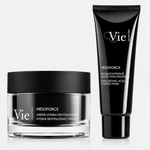 Two Vie Collection skincare products from the Mésoforce range displayed on a light grey background: a clear glass jar of Hydra Revitalizing Cream with a matte black lid beside a black tube of Hyaluronic Acid Vitamin Mask.