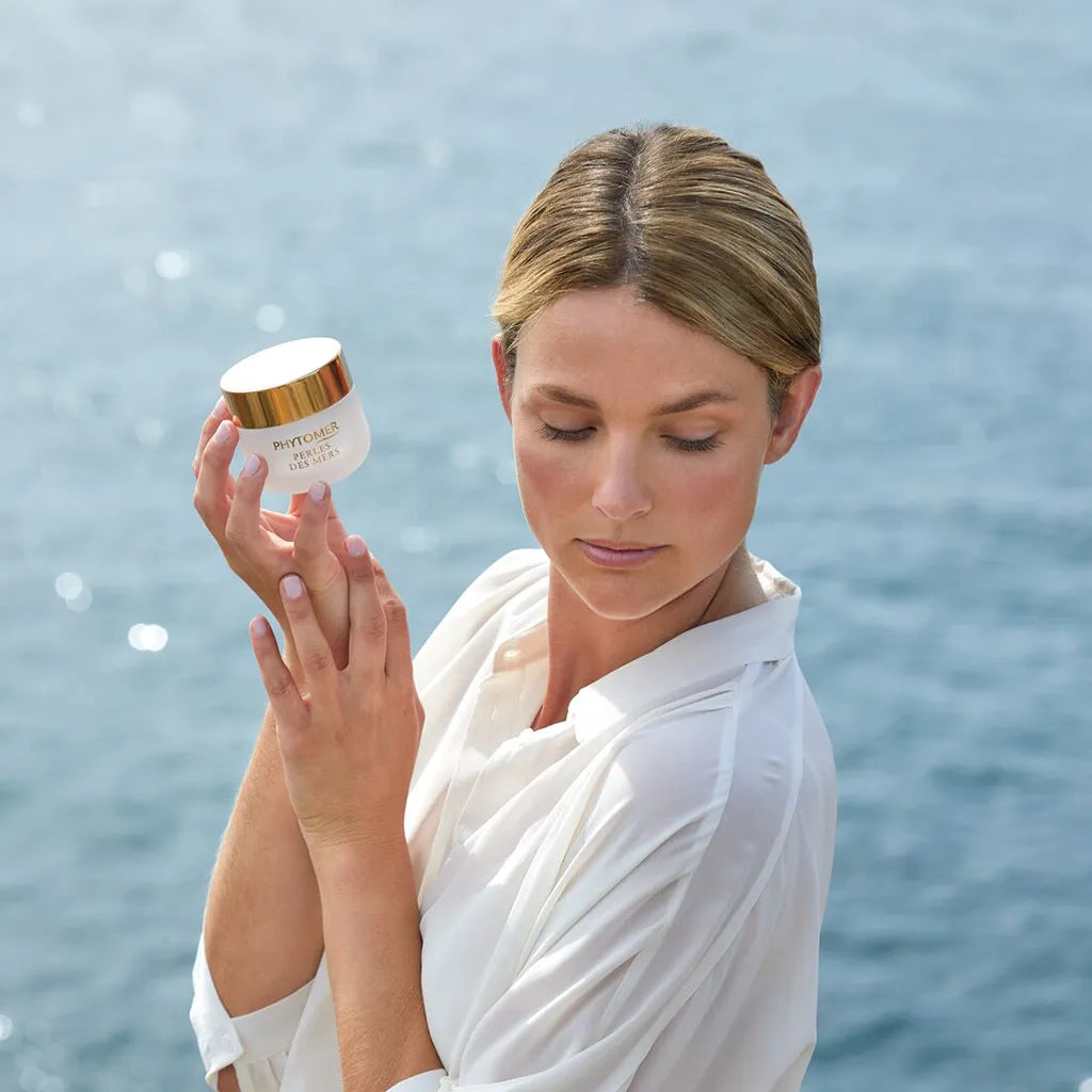 Woman holding a jar of PHYTOMER Perles Des Mers Longevity Cream 50ml with a blurred natural background