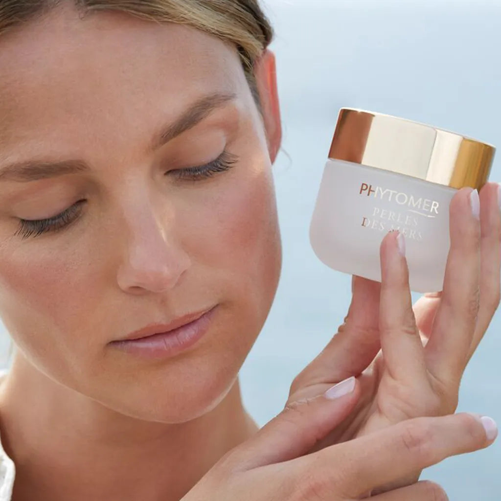 Woman holding a PHYTOMER Perles Des Mers Longevity Cream 50ml against a light blue background