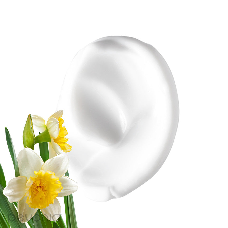 Pevonia Power Repair Marine Collagen Cream indicating texture and ingredients-White smear of cream next to a cluster of white and yellow daffodils indicating ingredients on a white background