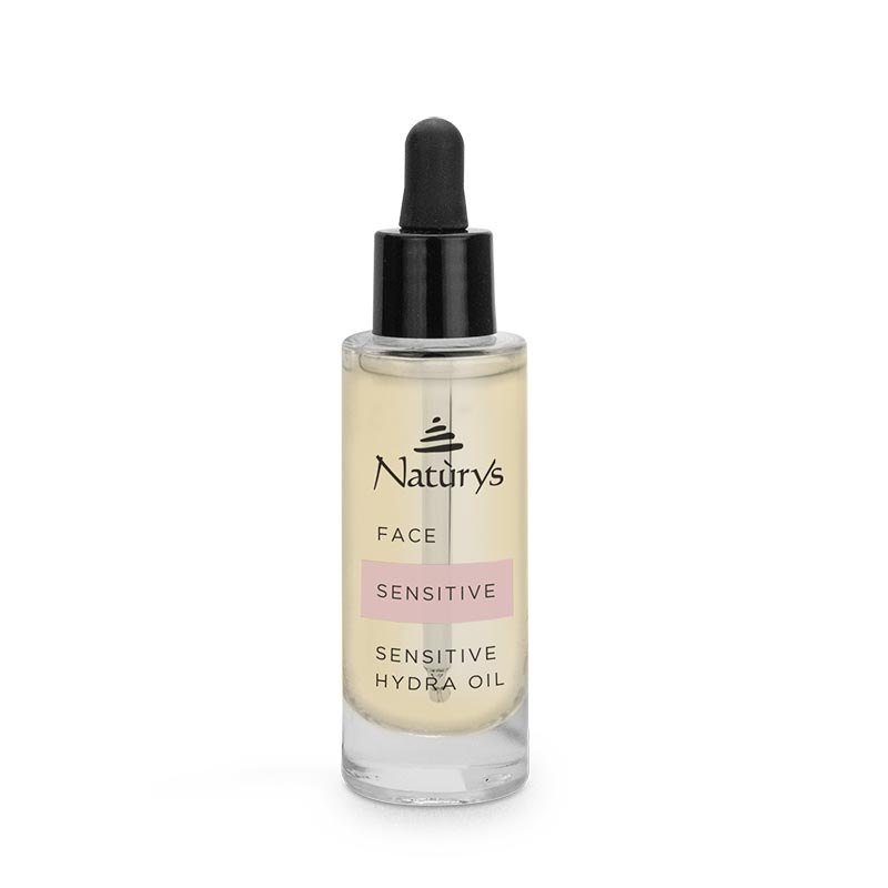 A clear glass bottle with a dropper containing face oil, labeled 'Naturys FACE SENSITIVE Sensitive Hydra Oil'.