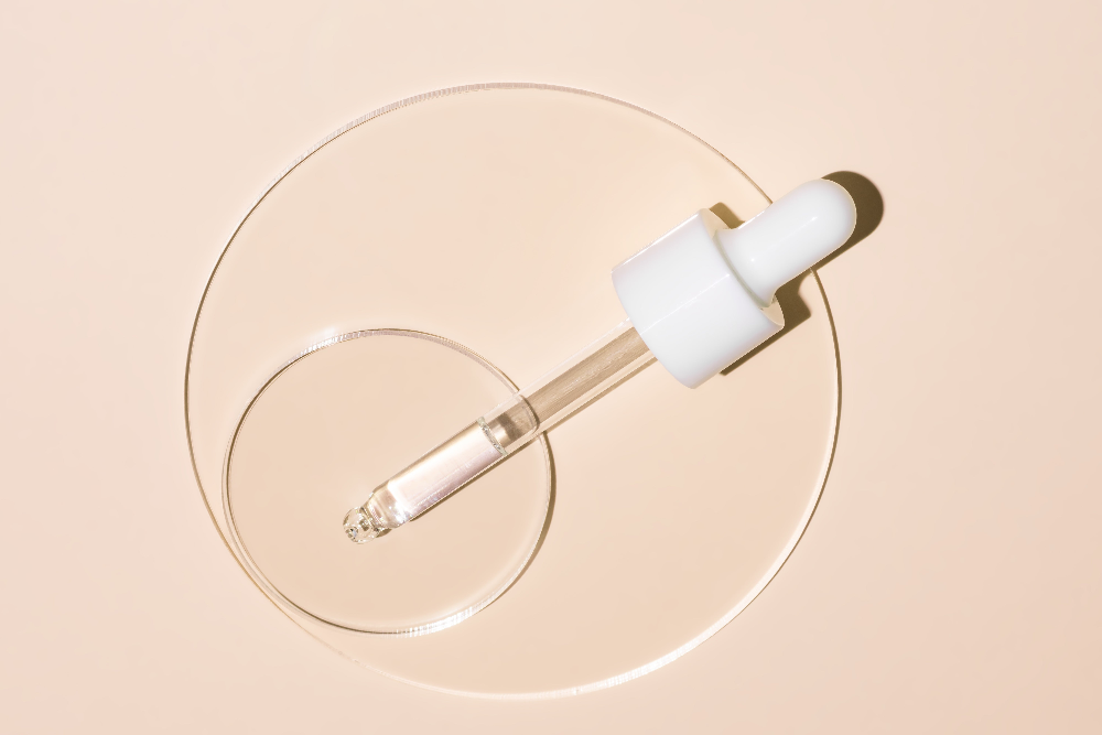 Skincare dropper with clear liquid on a beige background
