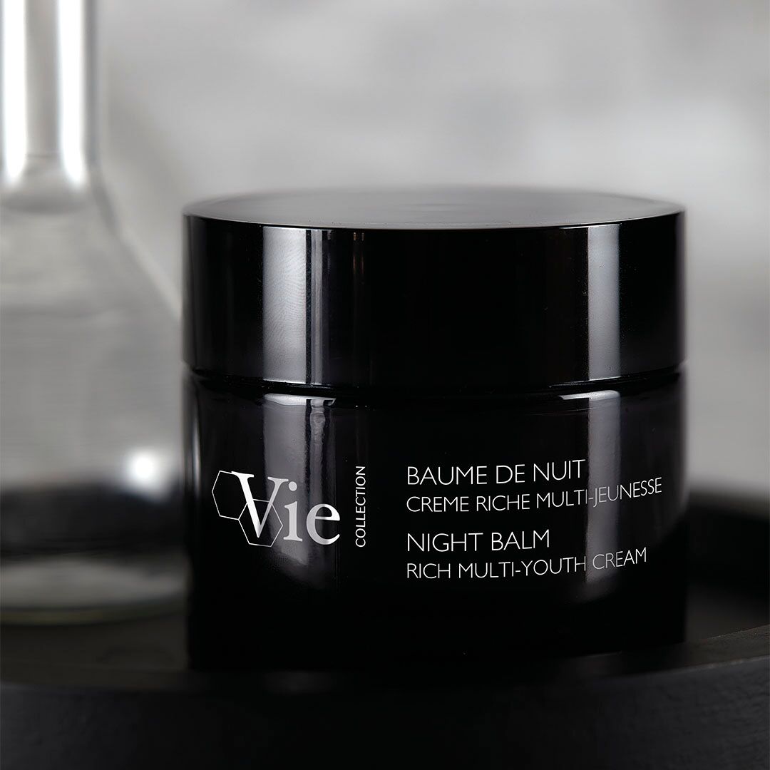 VIE COLLECTION Night Balm Rich Multi-Youth Cream 50ml on a reflective surface with a blurred background