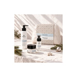 Naturys moisturising cleanser, serum, cream and white cosmetics bag in a sunlit Christmas setting with pine sprigs and ornaments.