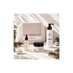 Naturys Sensitive micellar gel, facial oil, cream and white cosmetics bag in a sunlit Christmas setting with pine sprigs and ornaments.