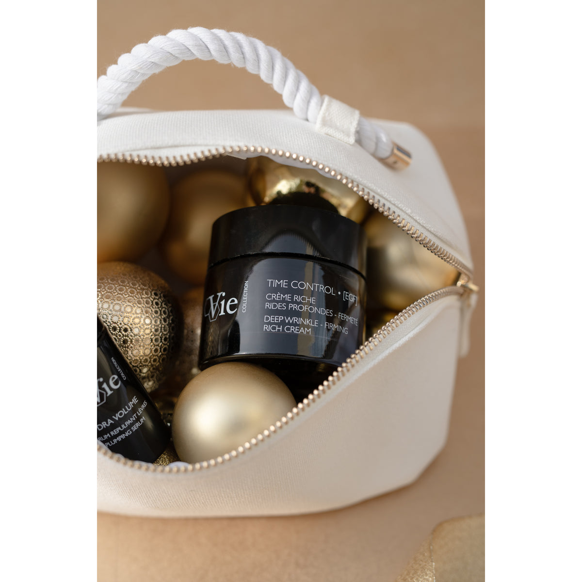 Close-up of Time Control cream and Hydra Volume lip serum inside the white gift pouch