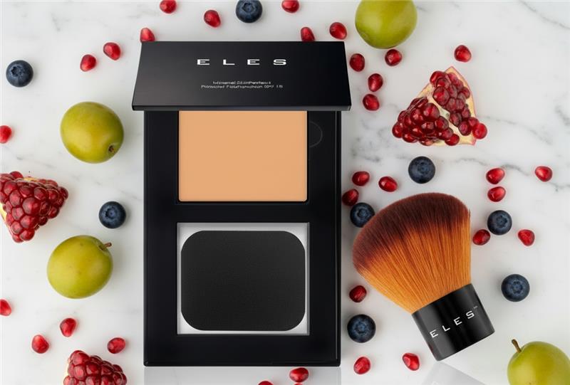 MAKEUP EYESIGHT powder compact with brush on a white marble surface with fruits