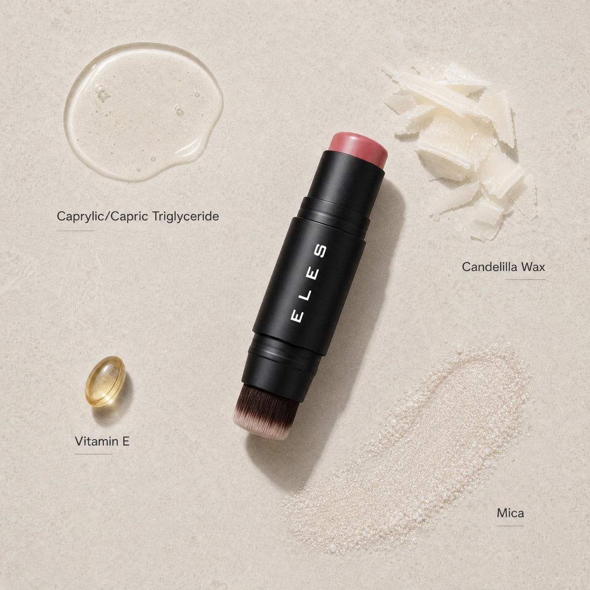 An ELES makeup stick with a black barrel and pink cap, shown on a textured beige background with ingredient callouts and swatches for caprylic/capric triglyceride, candelilla wax, vitamin E, and mica.