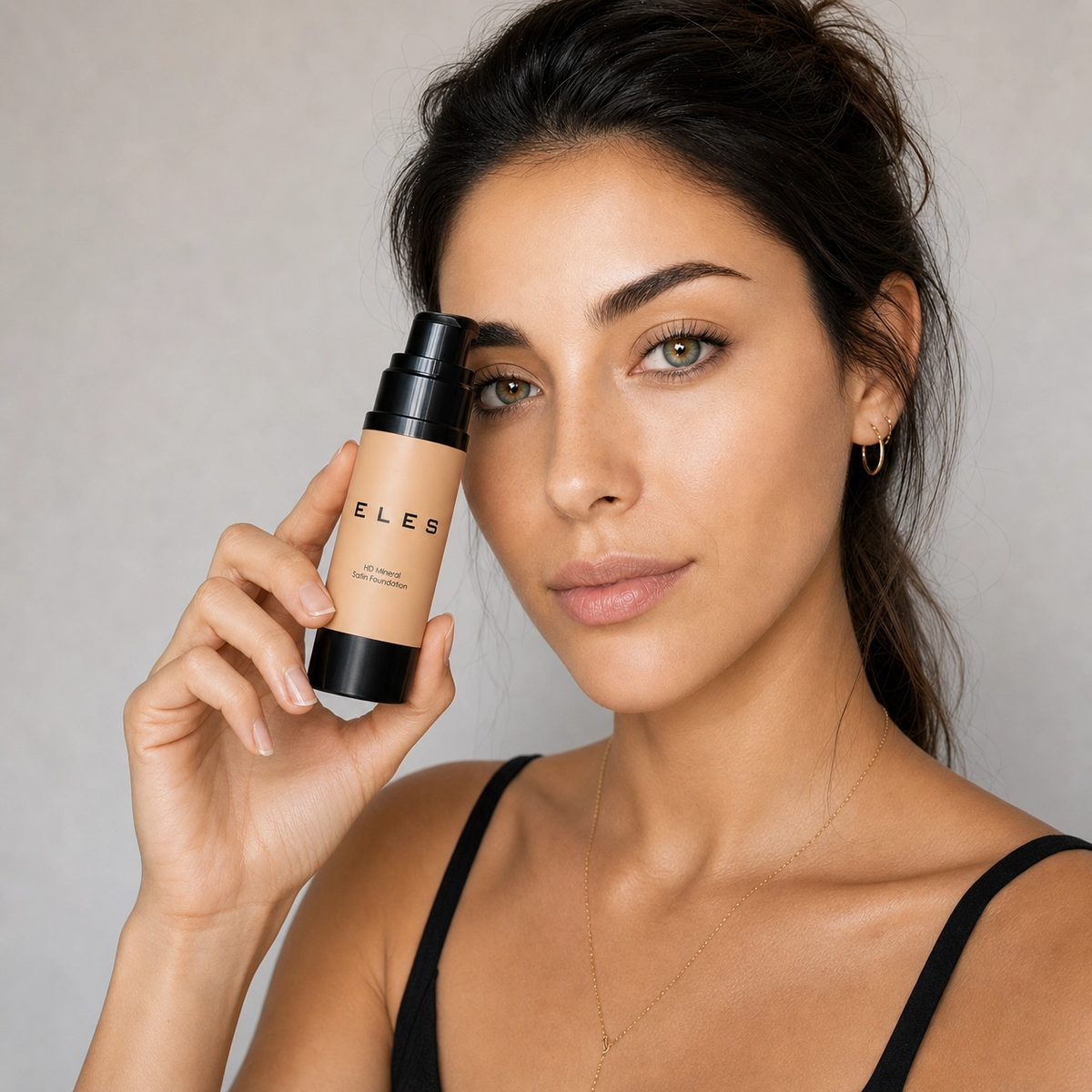 model holding a bottle of ELES HD Mineral Satin Foundation , light background