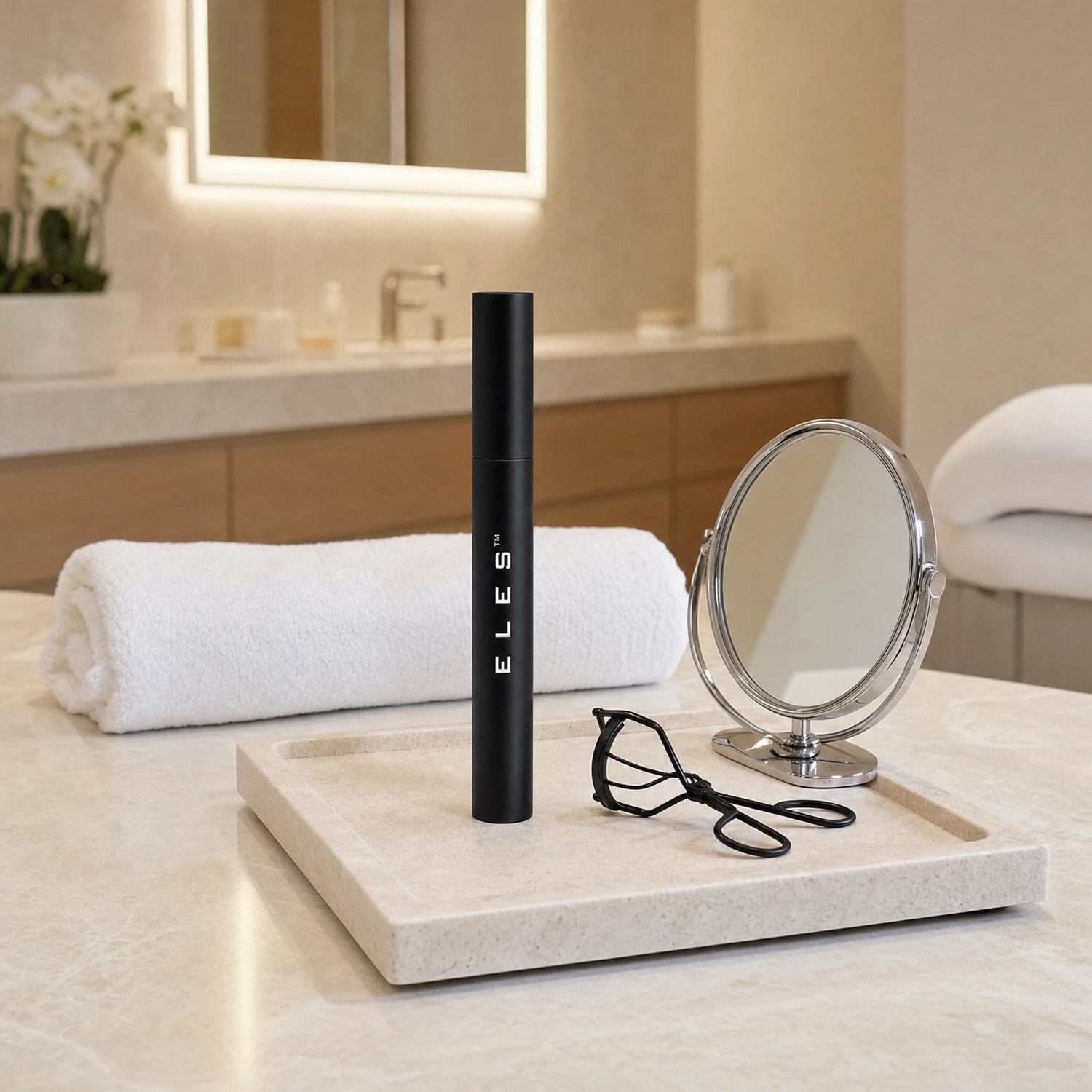 ELES Lash Fortify Waterproof Mascara Black standing upright on a stone tray with a lash curler and round mirror on a marble clinic bench inside a premium skin clinic treatment room, ideal for professional lash and eye finishing after facial treatments