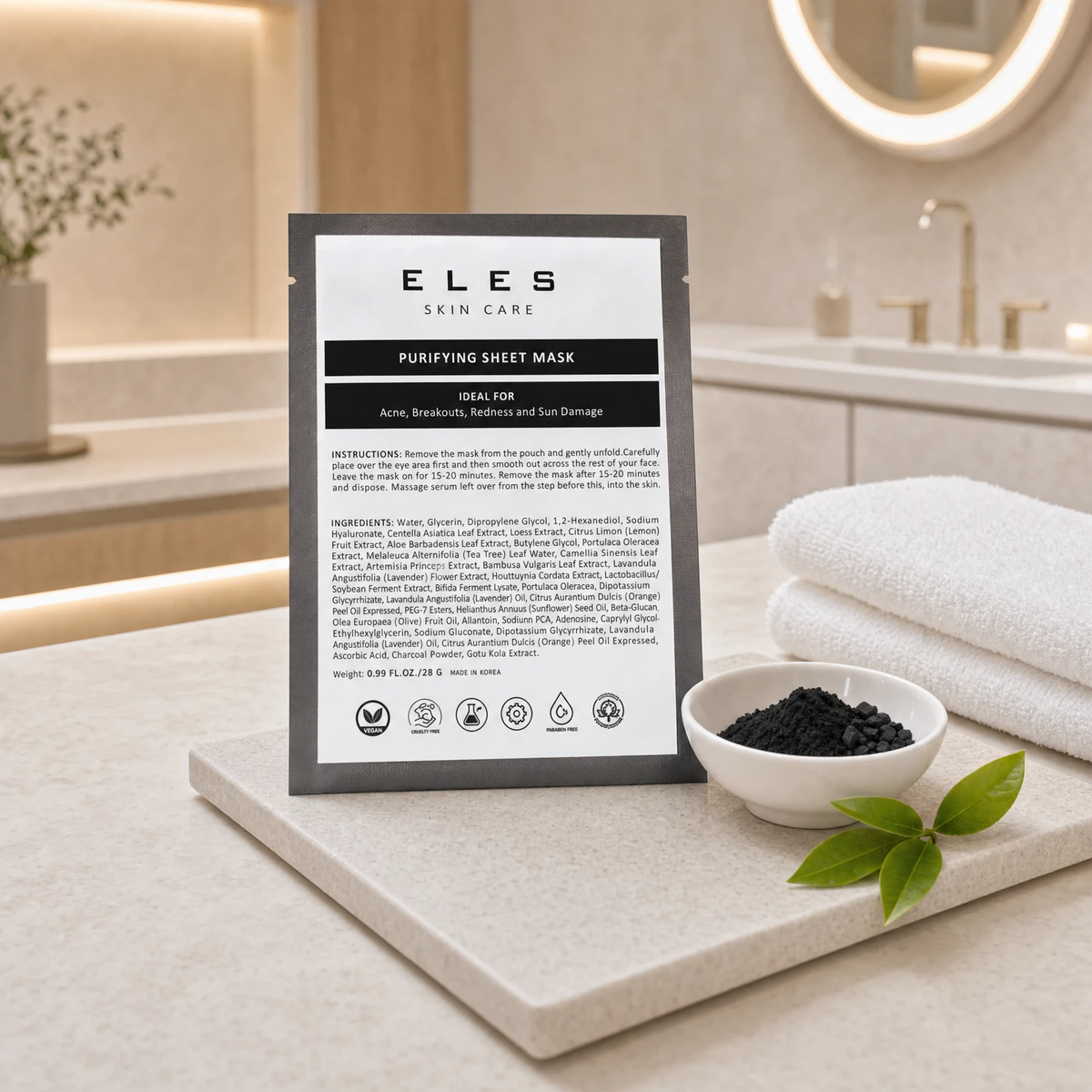 ELES Purifying Sheet Mask black foil sachet leaning against a stone tray with a white ceramic bowl of charcoal and green tea leaves on a marble clinic bench inside a premium skin clinic treatment room, ideal for professional purifying facial treatment preparation