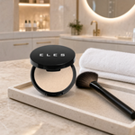 ELES Satin Illuminator 8g open hinged compact with fan brush on a stone tray on a marble clinic bench inside a premium skin clinic treatment room, ideal for professional highlighting and complexion finishing after facial treatments
