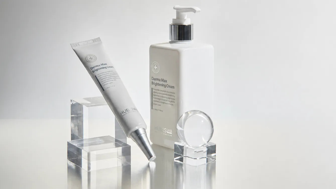 A hubislab skincare set featuring a white pump bottle and a white squeeze tube with silver accents, displayed on clear acrylic blocks against a light gray background.