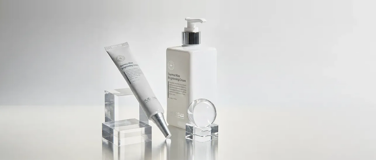 A hubislab skincare set featuring a white pump bottle and a white squeeze tube with silver accents, displayed on clear acrylic blocks against a light gray background.