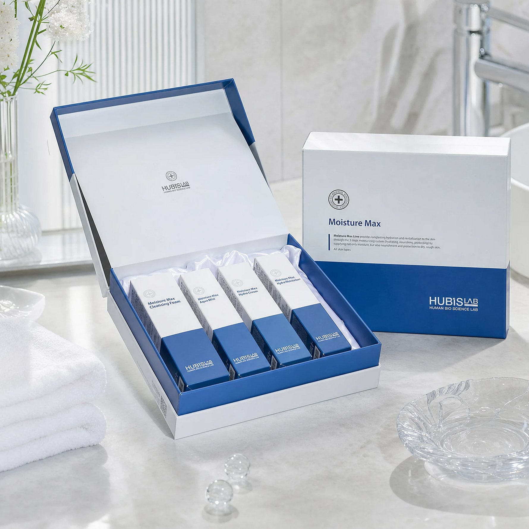 Hubislab Moisture Max Gift Set displayed in a premium bathroom setting with open presentation box, closed gift box, soft towels and clinical-luxury hydration styling.