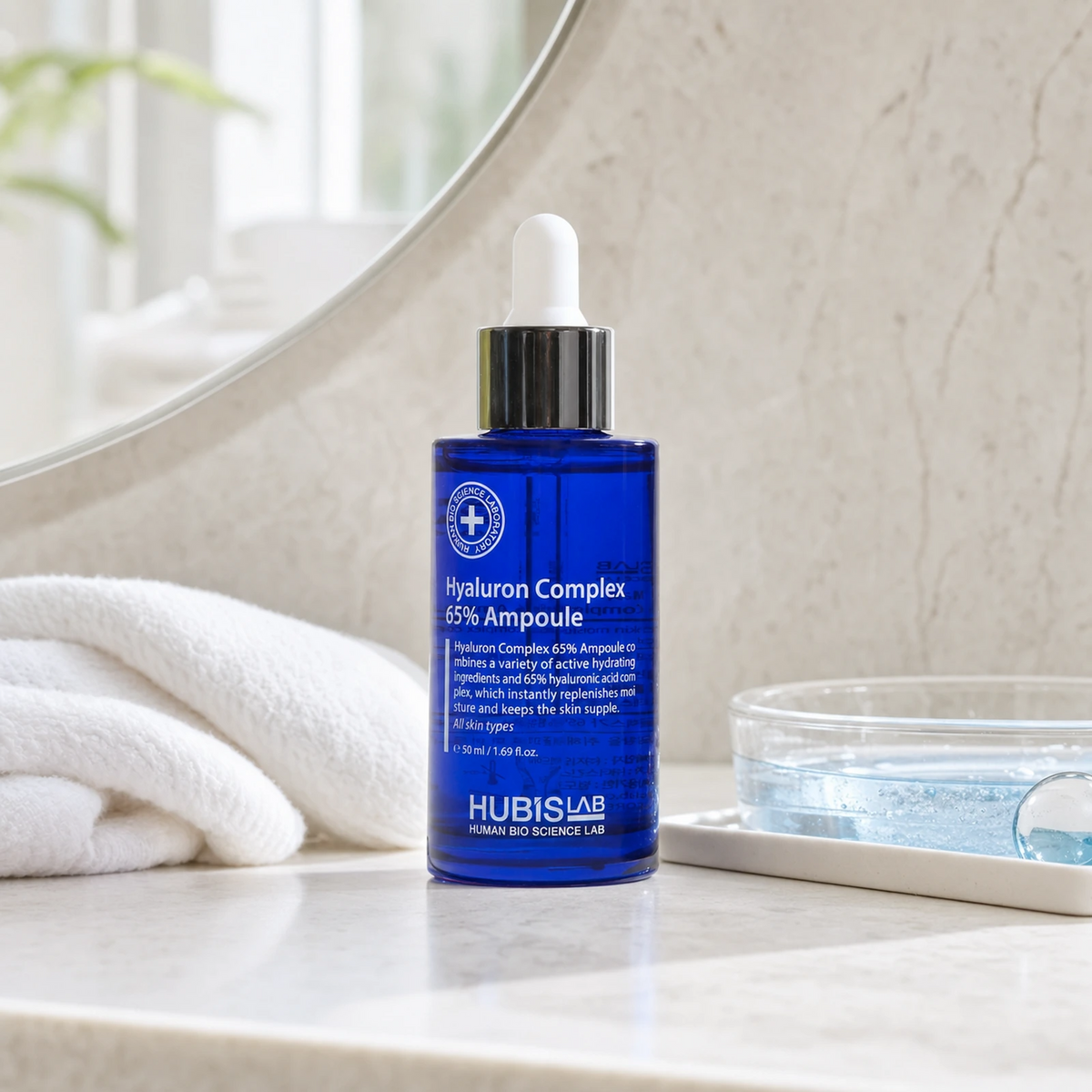 Hubislab Moisture Max Hyaluron Complex 65% Ampoule 50ml displayed on a clean premium bathroom vanity with a soft towel and blue hydration cue.