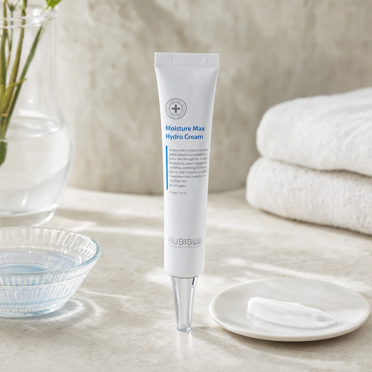 Hubislab Moisture Max Hydro Cream 40g displayed on a clean premium bathroom vanity with a soft towel, glass dish and refined cream texture cue.