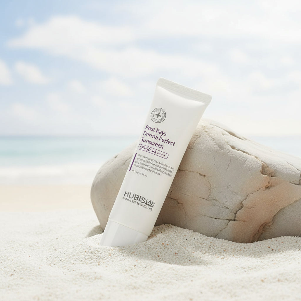 Tube HUBISLAB Post Rays Derma Perfect Sunscreen sunscreen on a sandy beach with rocks and sky in the background