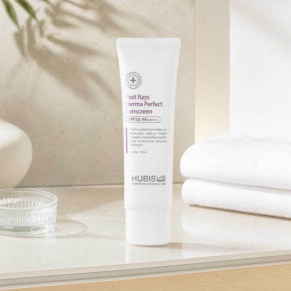 Hubislab Post Rays Derma Perfect Sunscreen SPF50 PA++++ 50g displayed on a clean premium bathroom vanity with soft towels and subtle sunlight styling.