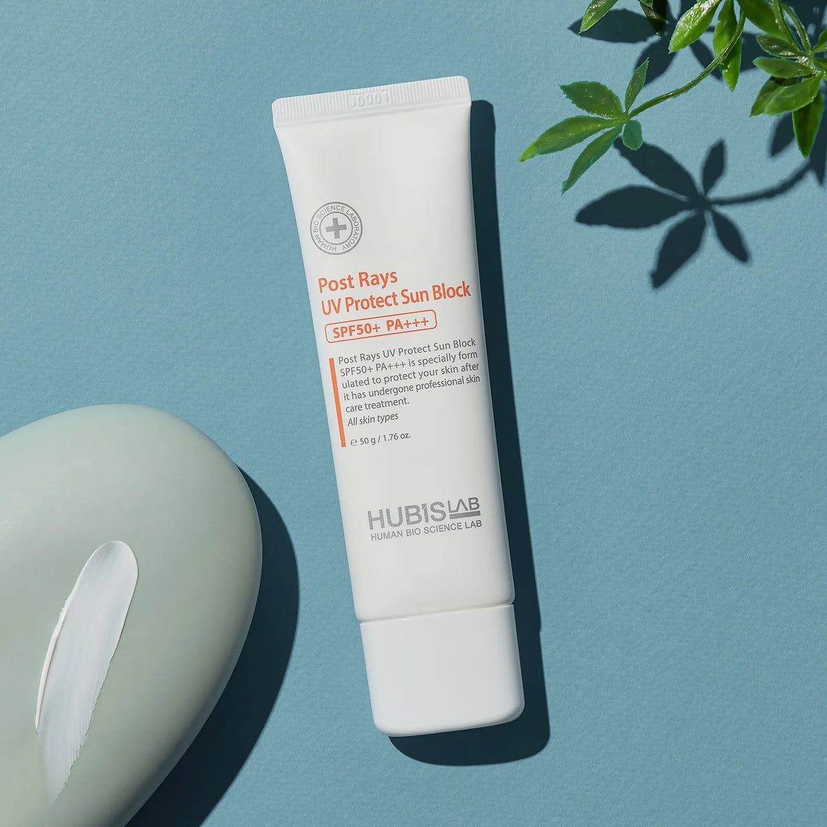 Tube of Hubis Lab Post Rays UV Protect Sun Block on a blue background with a plant leaf.