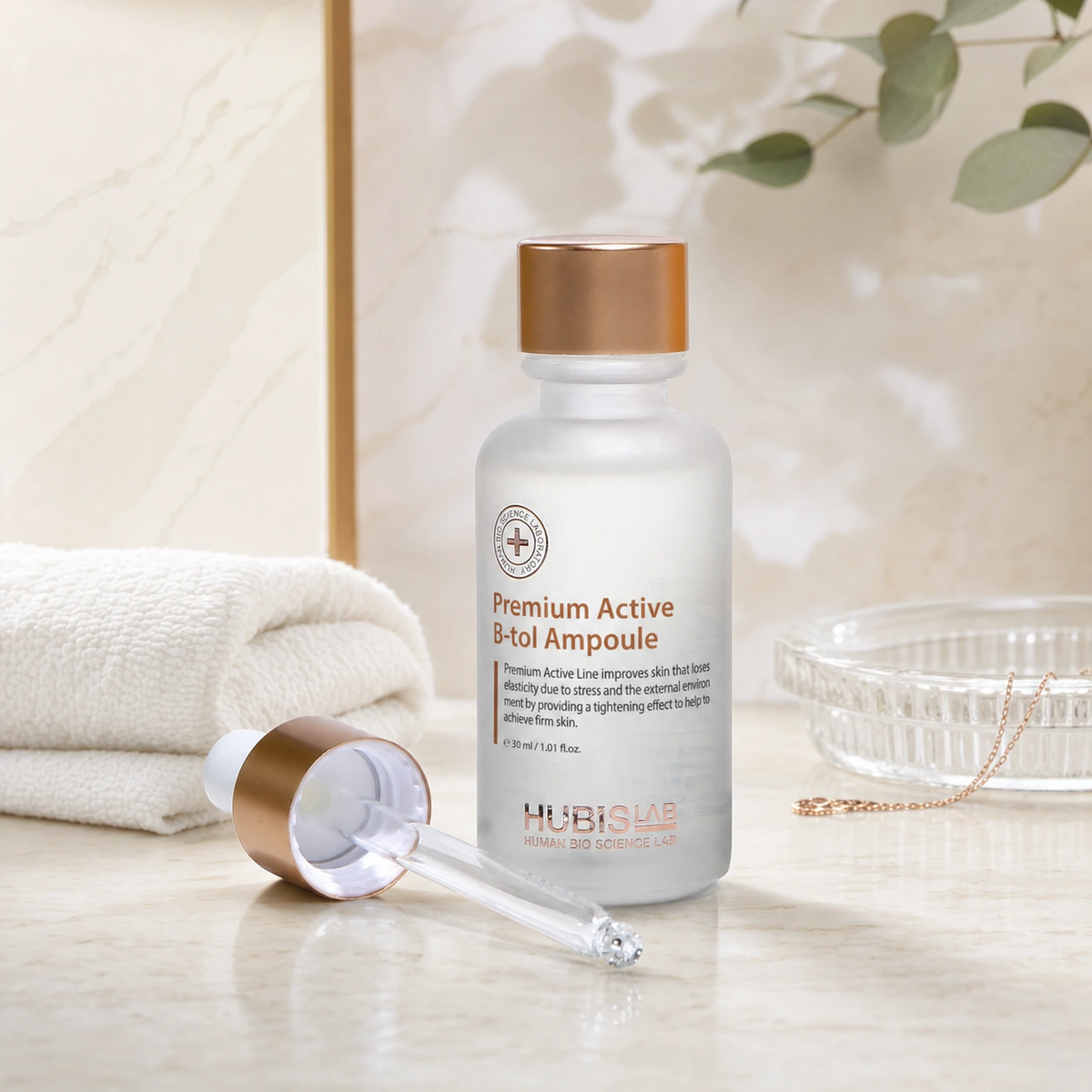 Hubislab Premium Active B-tol Ampoule 30ml displayed on a clean premium bathroom vanity with a soft towel, glass dish and copper serum styling.