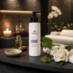 Naturys Anti-Age Cleansing Gel Oil 150ml on a dark slate spa tray with ceramic oil dish, argan oil vial, grape vine leaf sprig and white gardenia bloom in a luxury candlelit spa treatment room with white orchids