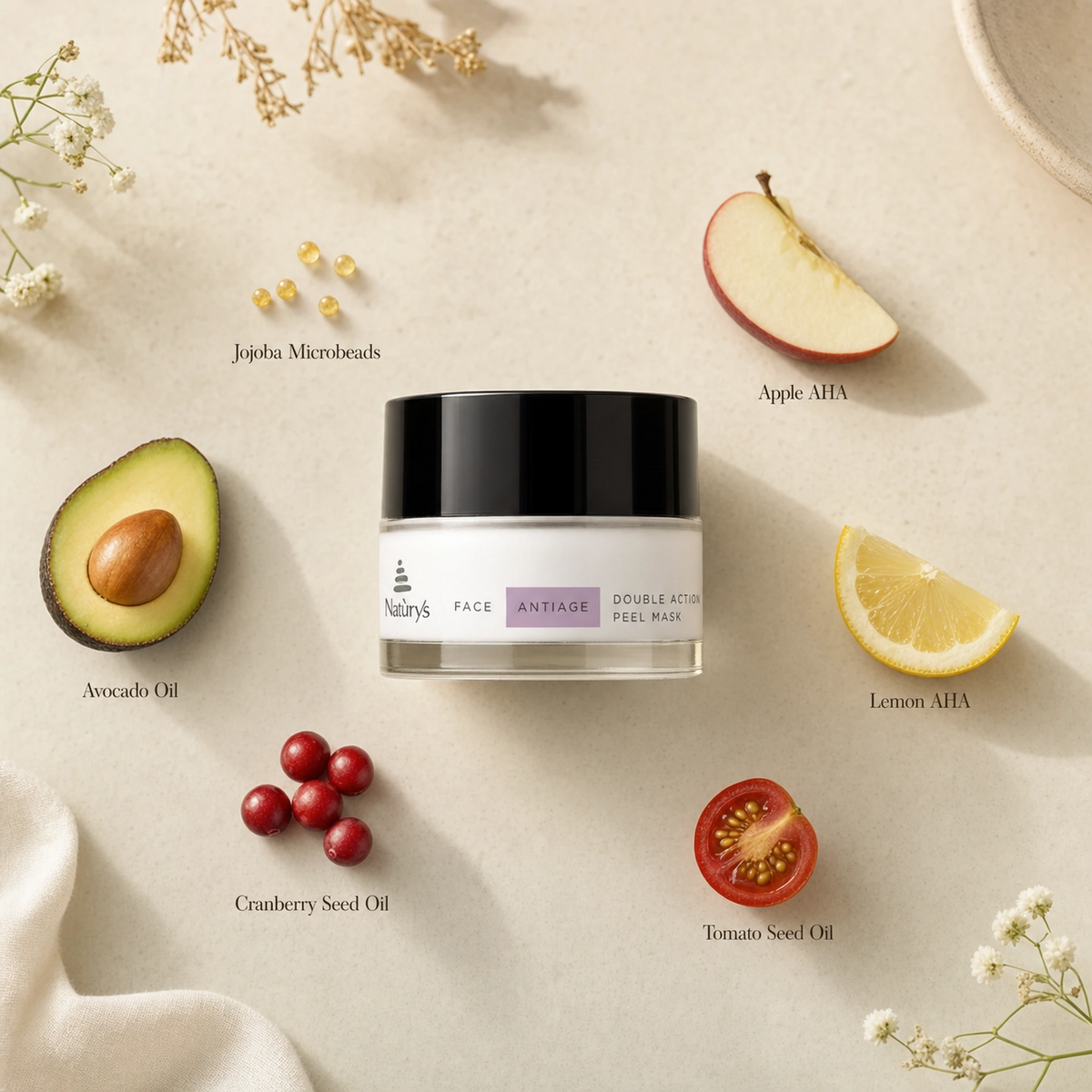 Naturys Anti-Age Double Action Peel Mask 30ml ingredient flatlay on warm cream surface with labelled ingredients: Jojoba Microbeads, Apple AHA, Lemon AHA, Avocado Oil, Cranberry Seed Oil, and Tomato Seed Oil