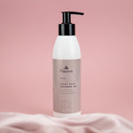 Naturys Body Silky Skin Shower Gel 250ml on a blush-pink marble spa ledge with sea buckthorn berries, fresh ginger root, orange half, and a draped pink silk cloth in a softly steamed luxury spa shower setting