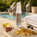 Naturys Tan Accelerating Spray Oil 100ml on a warm travertine poolside surface with a glass dish of golden carotenoid oil, annatto seeds, golden kelp, fresh blueberries and a white pool towel, with a luxury outdoor spa pool and tropical greenery in the background