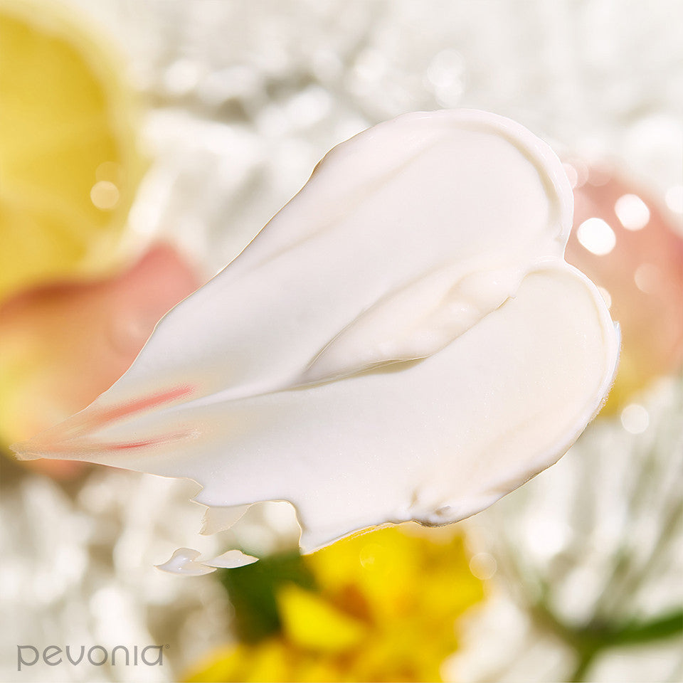 Pevonia Hyaluronic Acid Hydra Moisturizer smear of white cream  indicating texture and background flowers indicating ingredients