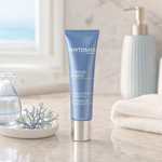 Phytomer Contour Radieux Smoothing and Reviving Eye Mask 30ml on a marble bathroom counter with teal coral in ceramic dish, glass vase with water, gold pump dispenser and white towels, premium at-home skincare setting