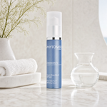 Phytomer Emergence Even Skin Tone Refining Serum 30ml on a marble bathroom vanity with glass vessel, white botanical, white towels and ceramic tray, premium at-home skincare setting
