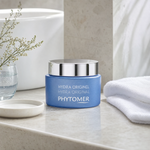 Phytomer Hydra Original Moisturising Melting Cream 50ml on a marble bathroom vanity with coastal botanicals in glass vessel, white towels and ceramic dish, premium at-home skincare setting