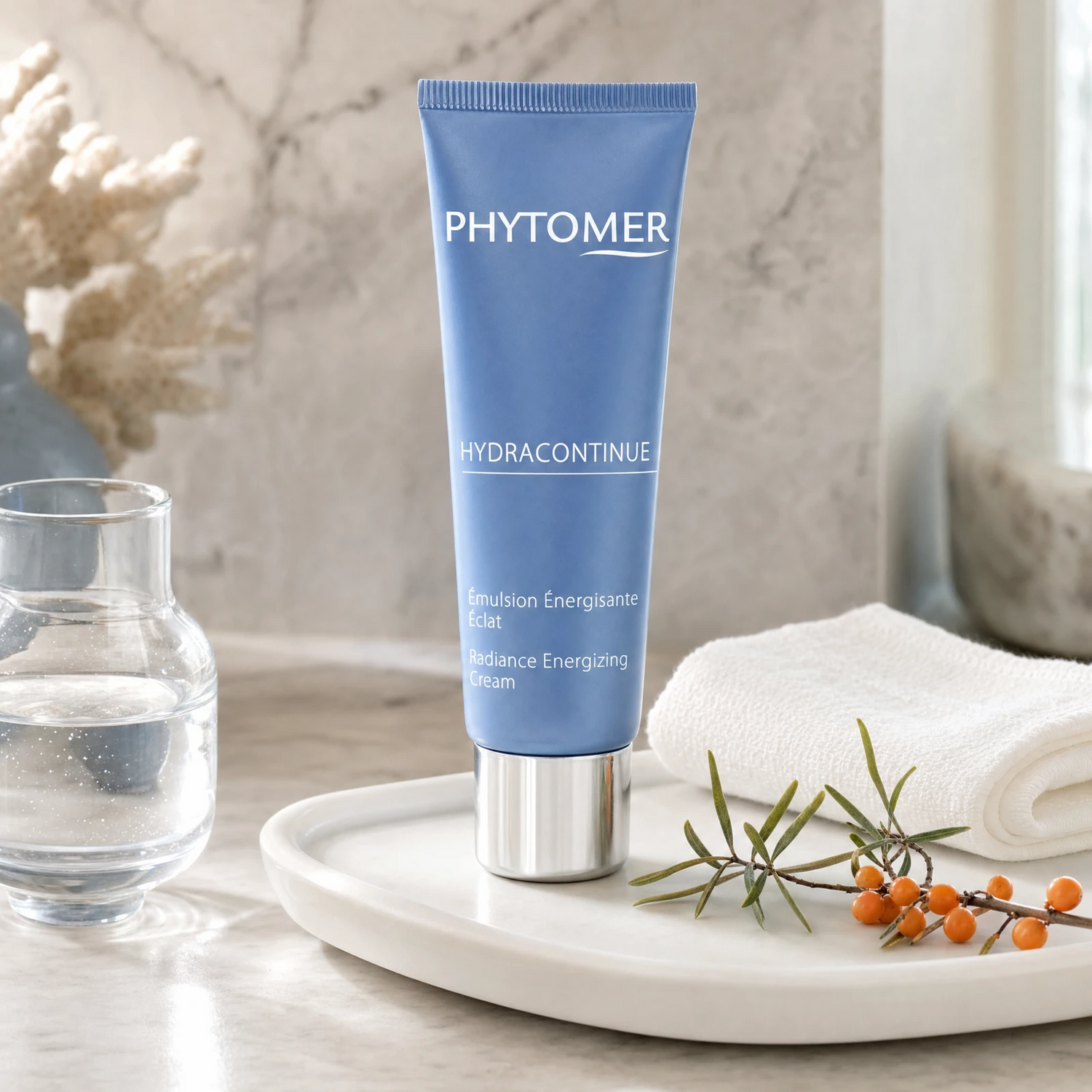 Phytomer Hydra Continue Radiance Energizing Cream 50ml on a marble bathroom vanity with glass vessel, sea buckthorn sprig, white towel and ceramic tray, premium at-home skincare setting