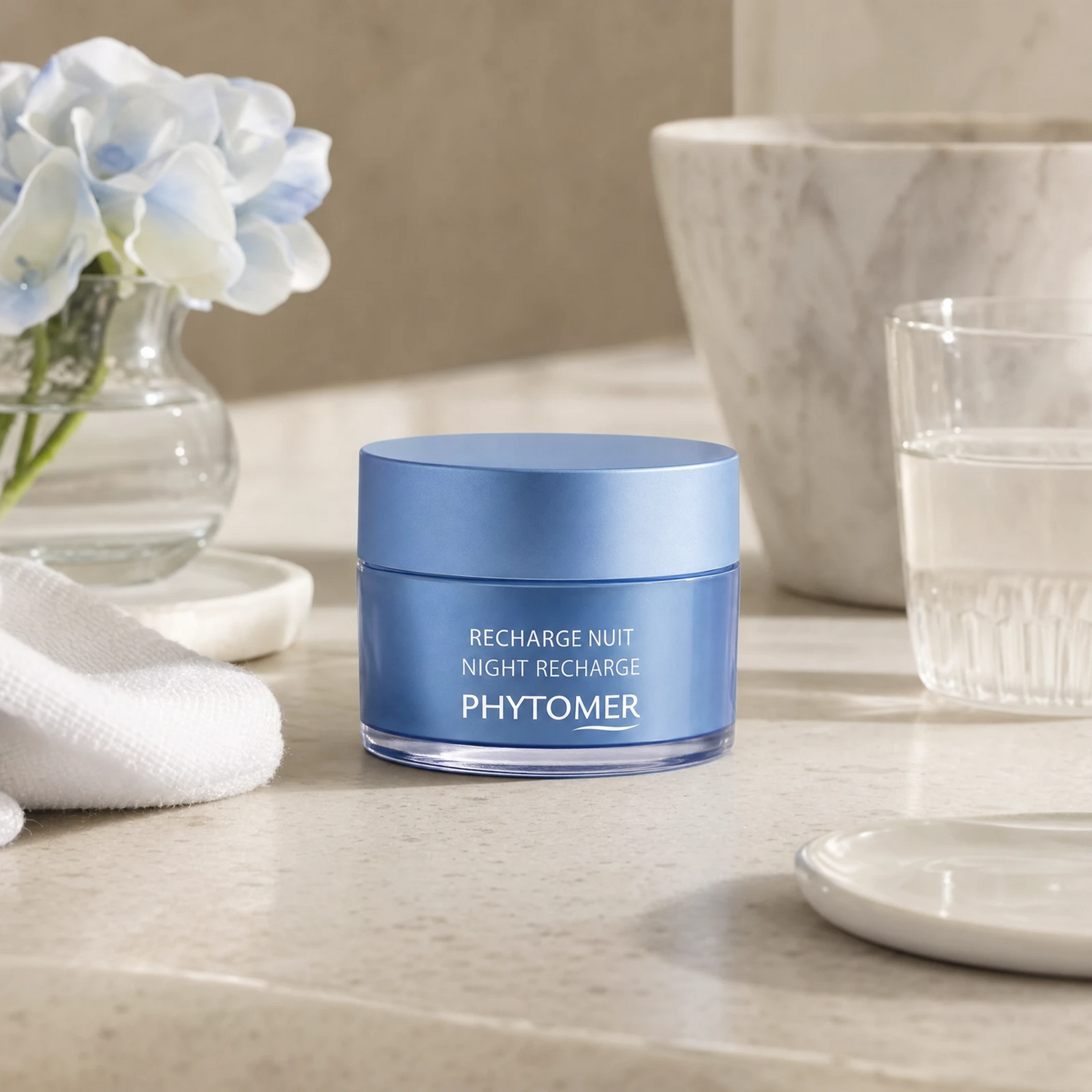 Phytomer Night Recharge Youth Enhancing Cream 50ml on a marble bathroom vanity with glass vessel, blue hydrangea, white towel and ceramic dish, premium at-home evening skincare setting