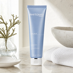 Phytomer Oligopur Purifying Cleansing Gel 150ml on a marble bathroom counter with teal coral in glass carafe, white ceramic soap dish, white waffle towel and soft backlit window, premium at-home skincare setting