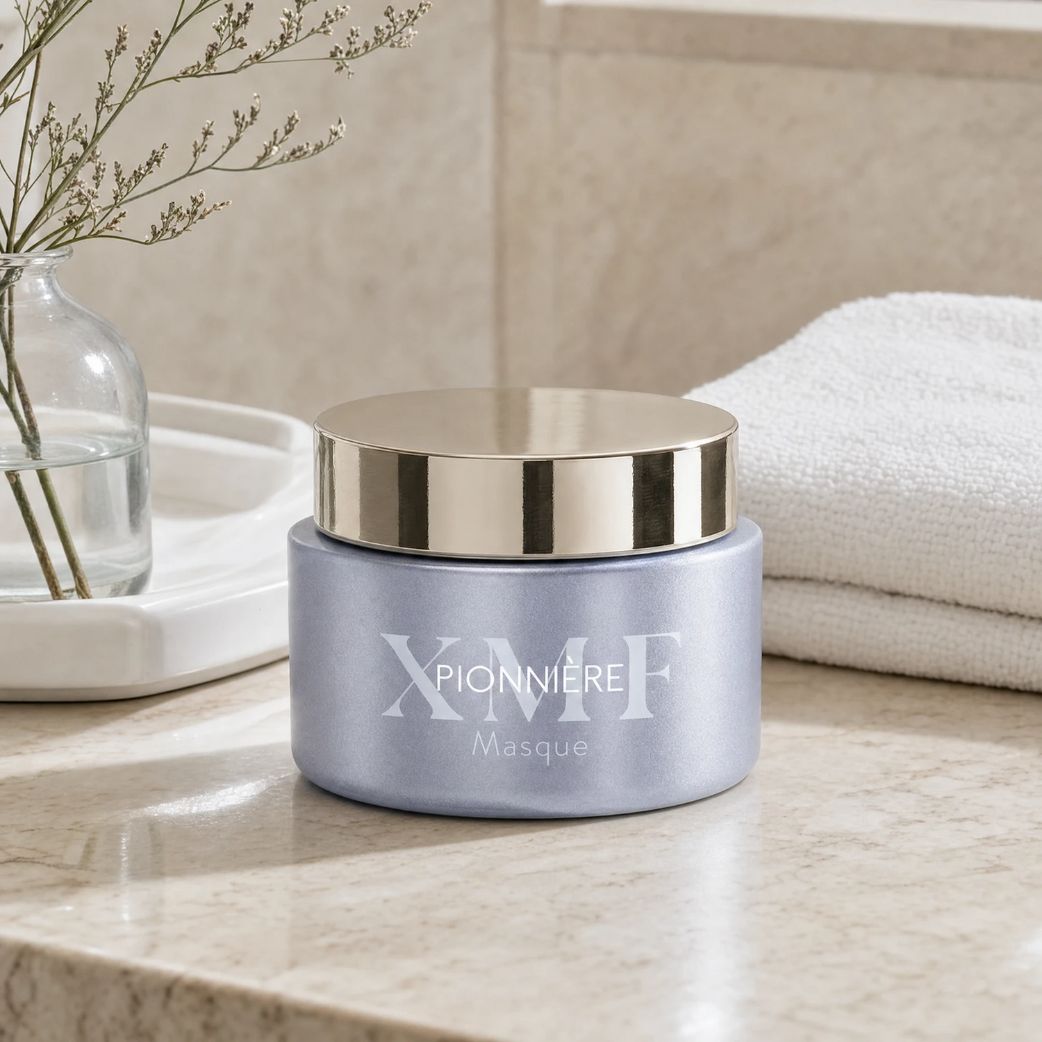 Phytomer Pionniere XMF Exfoliating Mask on a marble bathroom counter with gypsophila in glass carafe, white ceramic tray, white towels and warm dappled light, premium at-home skincare setting