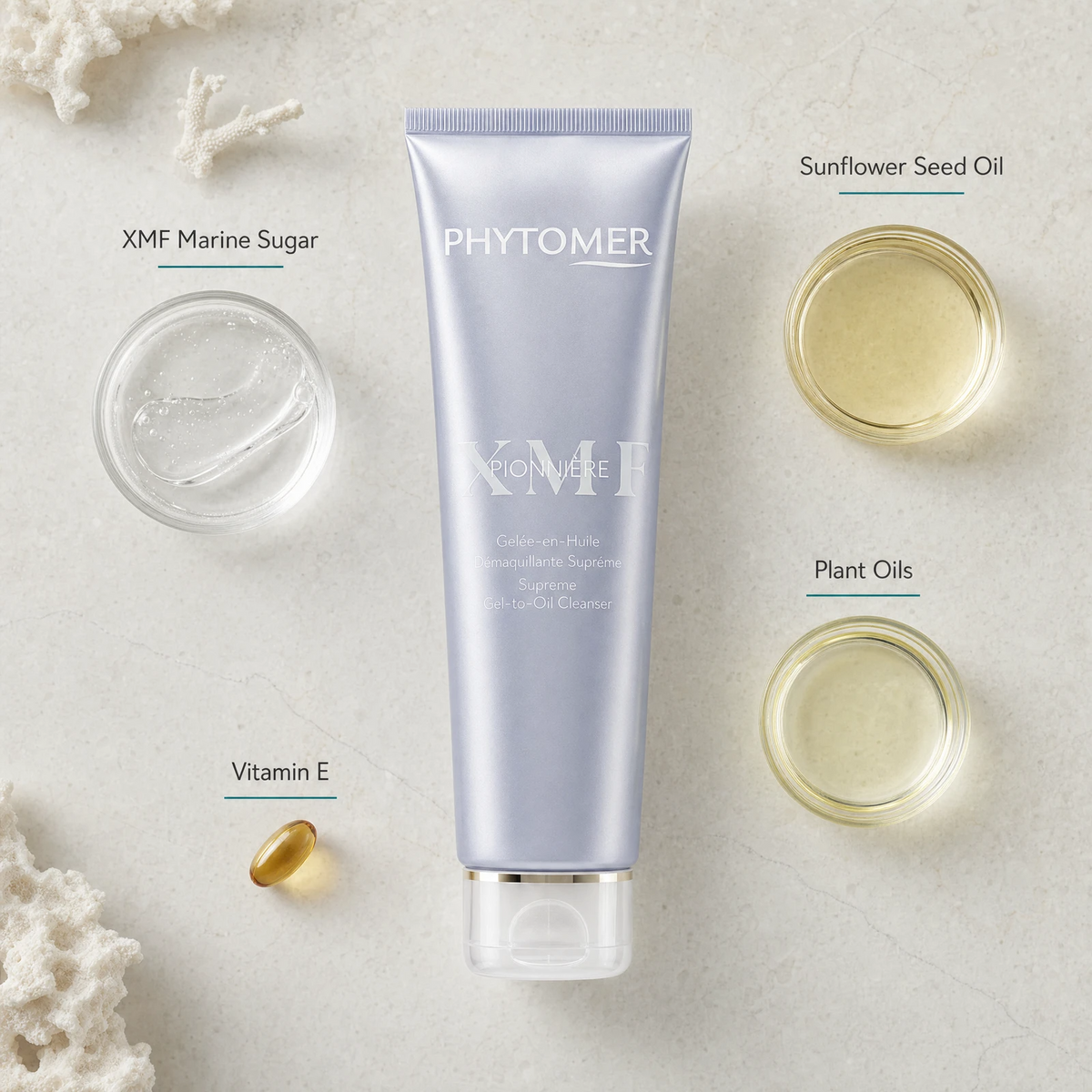 Phytomer Pionniere XMF Supreme Gel-to-Oil Cleanser 150ml is centered on a light stone background, surrounded by ingredient callouts and small ingredient containers: XMF Marine Sugar, Sunflower Seed Oil, Plant Oils, and a Vitamin E capsule.