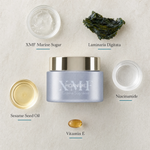 Phytomer Pionniere XMF Youth and Glow Supreme Cream flatlay on limestone surface with XMF Marine Sugar, Laminaria Digitata, Niacinamide, Sesame Seed Oil, and Vitamin E