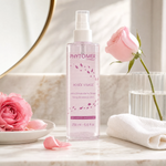 Phytomer Rosée Visage Toning Cleansing Lotion Mist Limited Edition 200ml on a marble bathroom counter with fresh pink rose in ceramic dish, scattered rose petals, rose in ribbed glass vase, white waffle towel and gold round mirror, premium at-home skincare setting