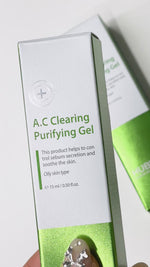 A hand squeezes Hubislab A.C Clearing Purifying Gel from the tube, showing its lightweight, clear texture before applying and gently rubbing a small amount into the skin on the wrist