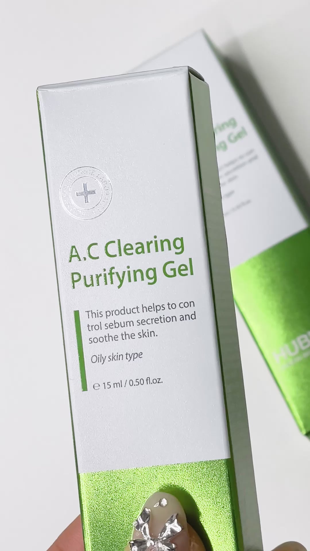 A hand squeezes Hubislab A.C Clearing Purifying Gel from the tube, showing its lightweight, clear texture before applying and gently rubbing a small amount into the skin on the wrist