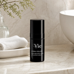 Vie Collection Hydra Volume Lip Plumping Serum 15ml on a marble bathroom counter with gypsophila in glass carafe, white ceramic tray, stacked white waffle towels and white basin in background, premium at-home skincare setting